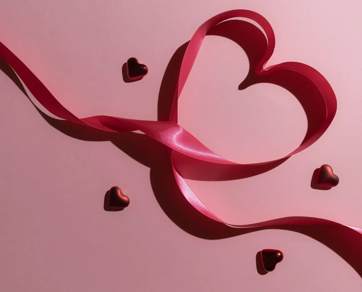 Cinta rosada en forma de corazón sobre fondo rosado